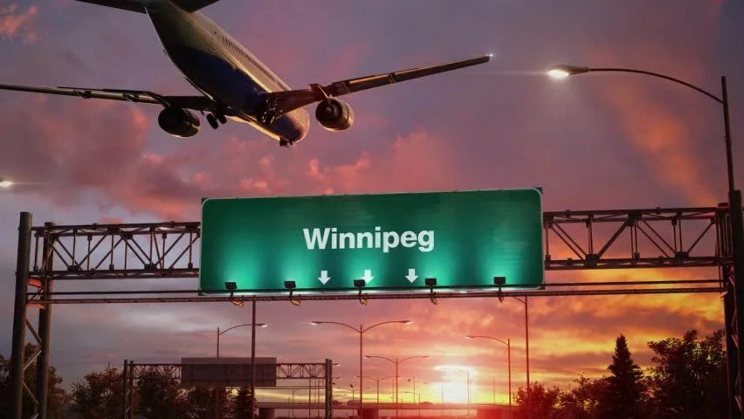 a plane flying over a sign that read Winnipeg on it during sun set